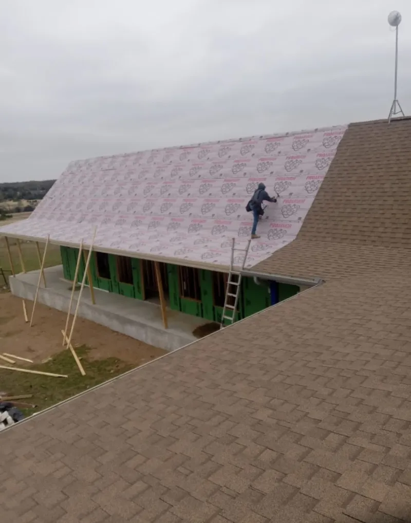Worker preparing underlayment for a metal roof installation in Kermit